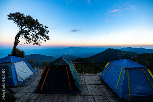 View of tents camping at the campsite in the woods with mountain range background. View of tents with mountain and beautiful sky background. Nature tourisium and tents camping concept.