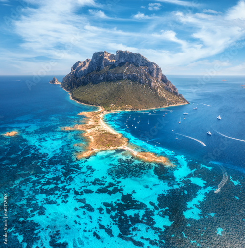 Aerial view of sandy beach on amazing Tavolara island in Sardinia, Italy. Top view of clear blue sea, boat, yachts, mountain, sky with clouds at summer sanny day. Colorful seascape with azure water