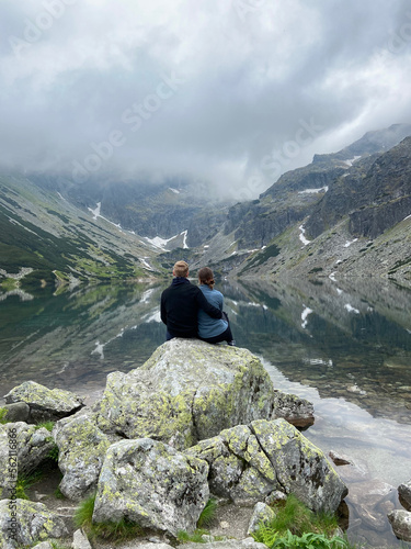 a couple are in the mountains near a lake