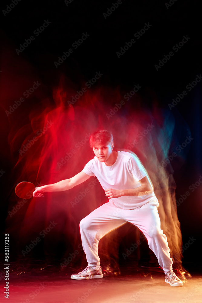 young man playing table tennis in mixed neon light