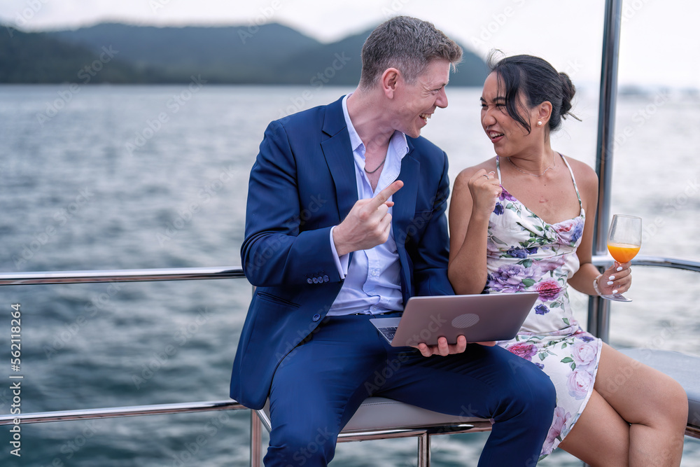 Business man and girl friend on holiday sailing on the yacht check laptop and get good news Business man and girl friend on holiday sailing on the yacht check laptop and get good news
