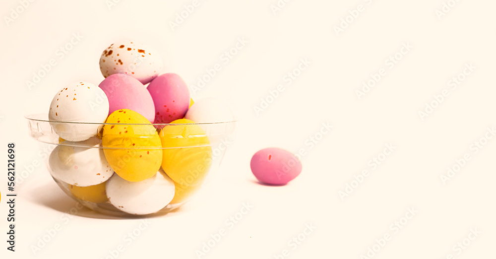 Colorful chocolate Easter eggs on beige background with copy space
