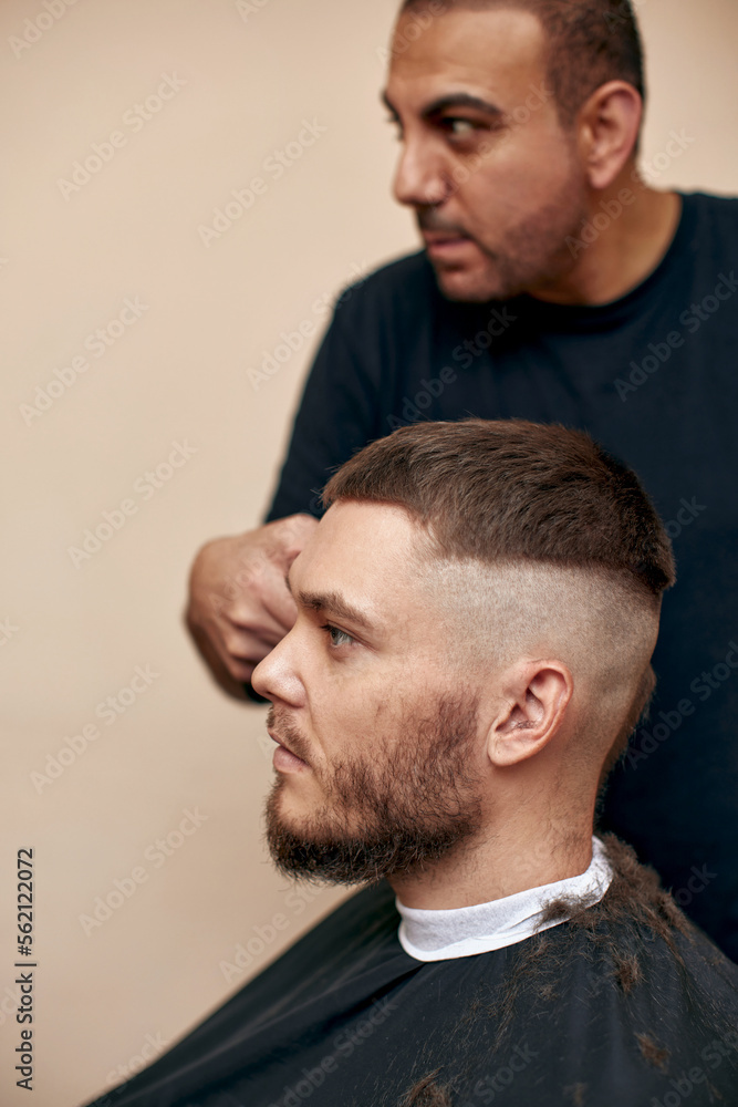 Fototapeta premium Barber shaving caucasian man in barber shop