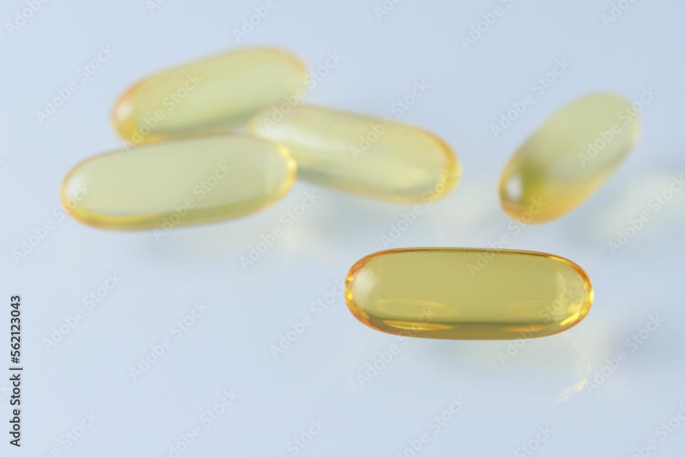 Omega 3 or fish oil capsule closeup on light blue background. Food supplement for healthy or cosmetic body care. Omega 3 or fish oil capsule closeup on light blue background. Food supplement for healthy or cosmetic body care.