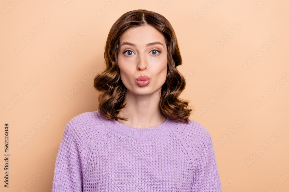 Photo of good mood pretty nice woman with curly hairdo dressed knit sweater pouted lips send kiss isolated on beige color background Photo of good mood pretty nice woman with curly hairdo dressed knit sweater pouted lips send kiss isolated on beige color background
