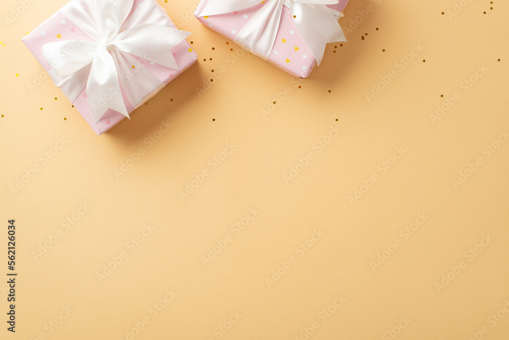 Valentine's Day concept. Top view photo of light pink gift boxes with white ribbon bows and golden sequins on isolated pastel beige background with empty space Valentine's Day concept. Top view photo of light pink gift boxes with white ribbon bows and golden sequins on isolated pastel beige background with empty space