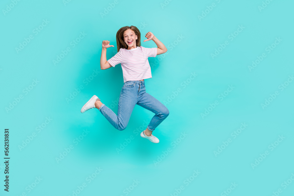 Full length photo of cool funky lady wear striped t-shirt pointing thumbs herself jumping high isolated turquoise color background