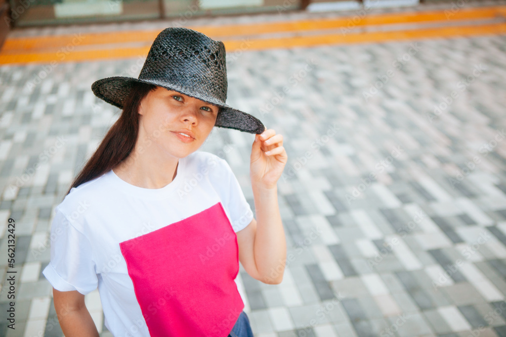 Smiling woman in black hat with long hair outdoors in summer, with copy space	