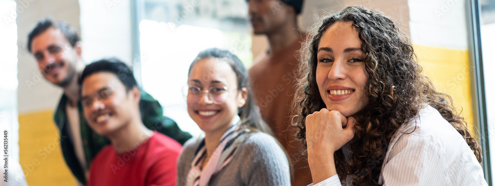 Obraz premium Horizontal banner or header with university students multiethnic team studying together on a new project in creative coworking classroom - Bright filter with focus on first woman on left