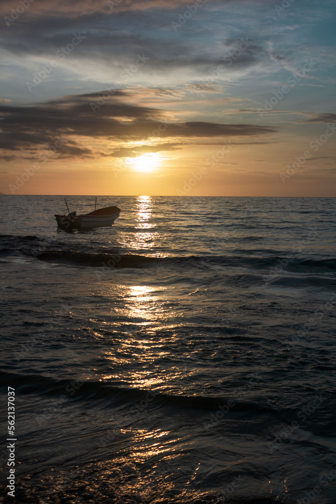 Sunset in the blue sea over a boat in gentle waves