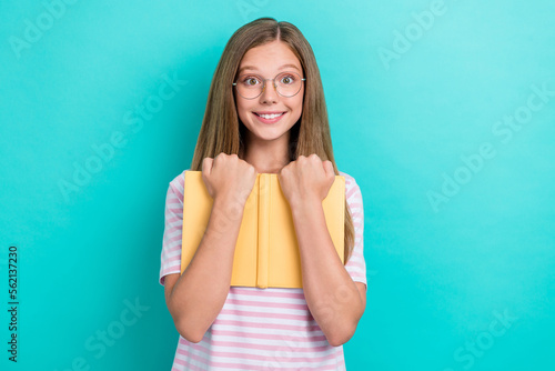 Photo of cheerful smart girl toothy smile arms hold hug book isolated on turquoise color background