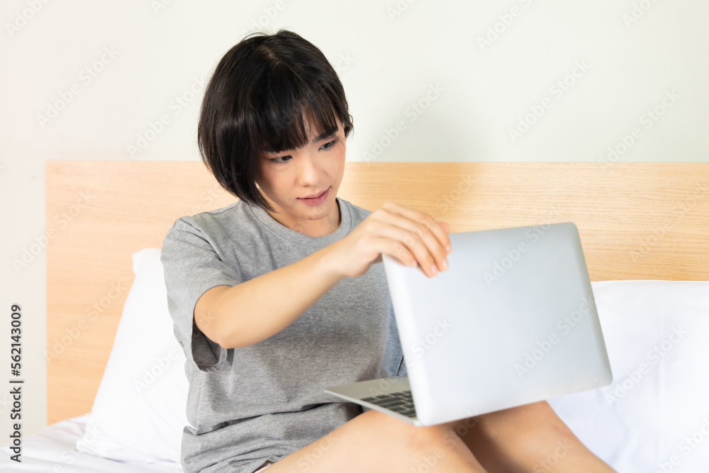 Serious asian woman starting working at home on her bed, concept of home office, working at home, work anywhere, telework, digital nomad Serious asian woman starting working at home on her bed, concept of home office, working at home, work anywhere, telework, digital nomad