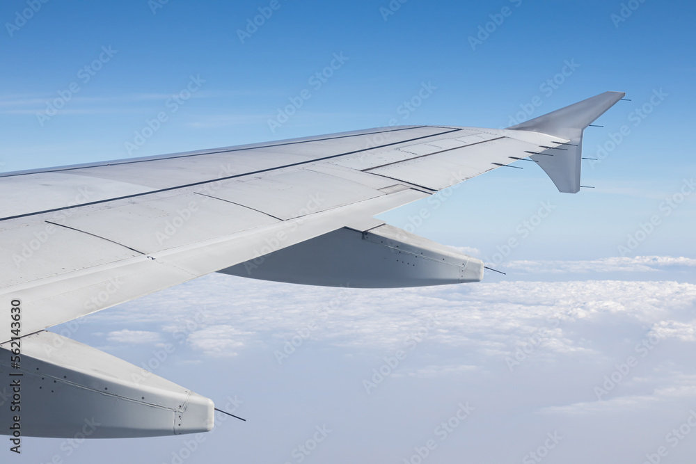 the wings of an airplane flying above the morning clouds the wings of an airplane flying above the morning clouds