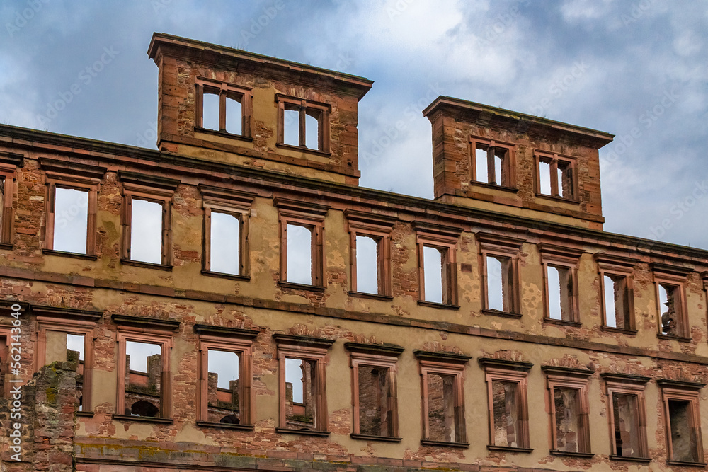 Close-up view of the façade ruin of the former residential palace called Englischer Bau with its stucco decorated window fronts rising high into the cloudy blue sky, a part of the Heidelberger Castle.