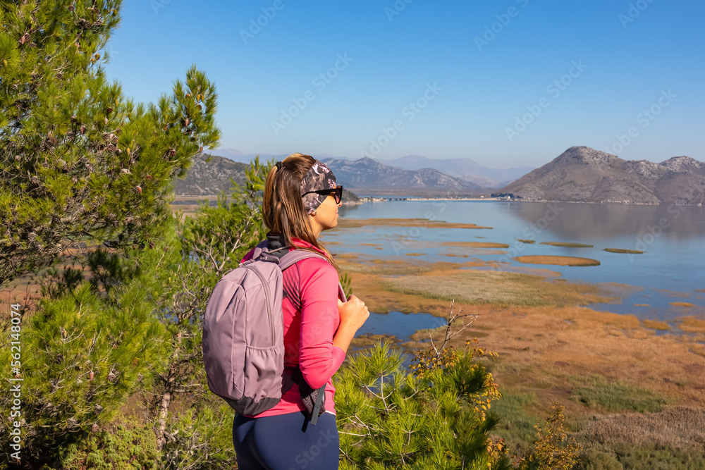 Rear view of woman with panoramic view of Lake Skadar National Park in autumn seen from Virpazar, Bar, Montenegro, Balkans, Europe. Stunning travel destination in Dinaric Alps near Albanian border