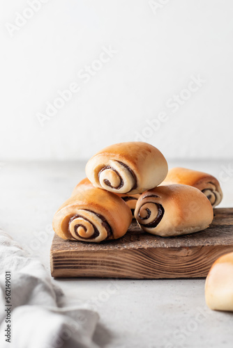 Freshly baked cinnamon Rolls for breakfast on wooden board on white kithen table on white background with text space. Easter traditional pastry food