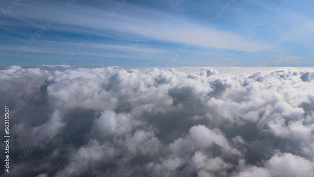 Aerial view from airplane window at high altitude of earth covered with white puffy cumulus clouds Aerial view from airplane window at high altitude of earth covered with white puffy cumulus clouds