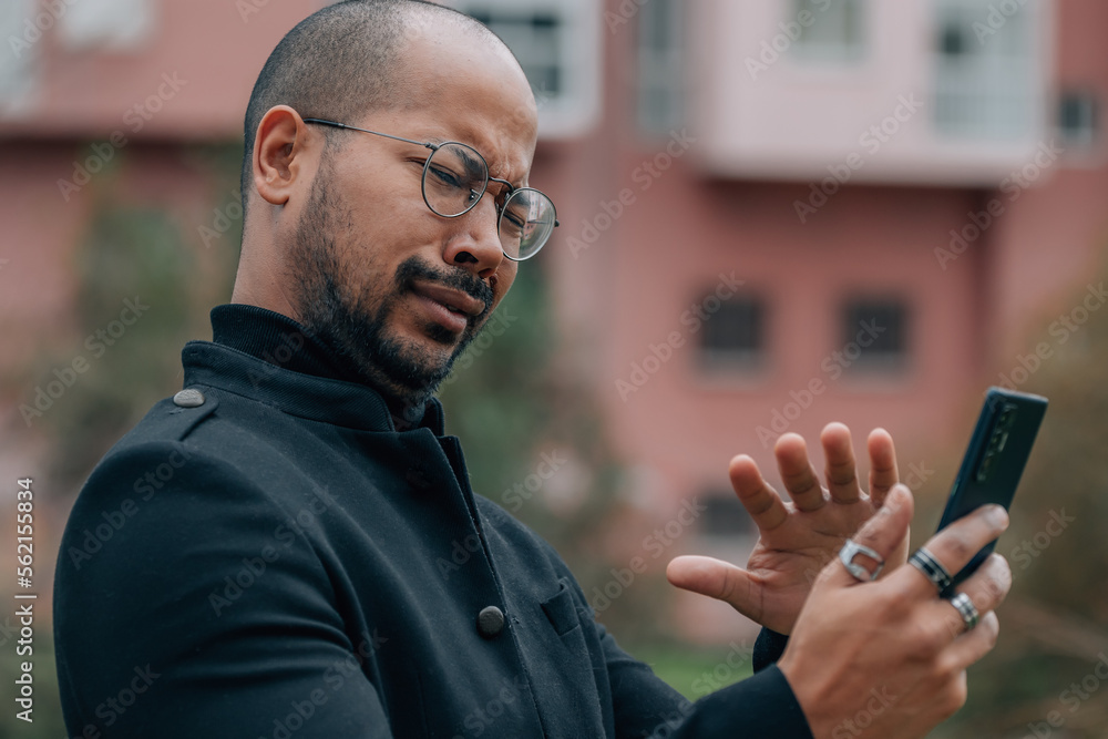 man in the street looking at the mobile phone or smartphone with expression of rejection man in the street looking at the mobile phone or smartphone with expression of rejection