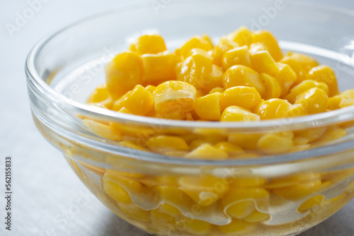 A closeup view of a glass condiment cup of canned corn kernels. photo