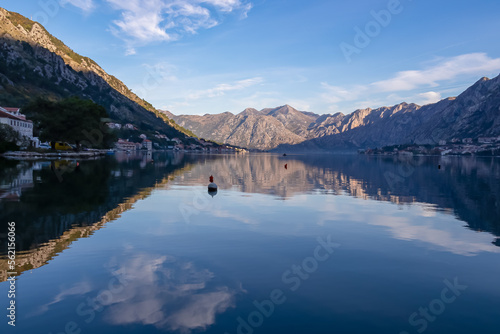 Panoramic view of bay of Kotor at sunrise in summer, Adriatic Mediterranean Sea, Montenegro, Balkans, Europe. Fjord winding along coastal towns. First sunbeams on Lovcen mountains. Water reflection © Chris