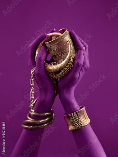 magenta woman's hands with gold jewelry. Oriental Bracelets on a black painted hand. Gold Jewelry
