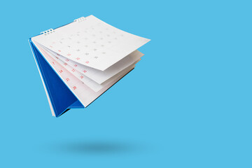 White paper desk calendar flipping page isolated on blue background