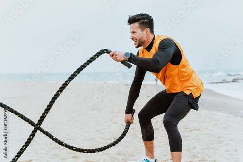 young athlete training in the morning on the beach with ropes