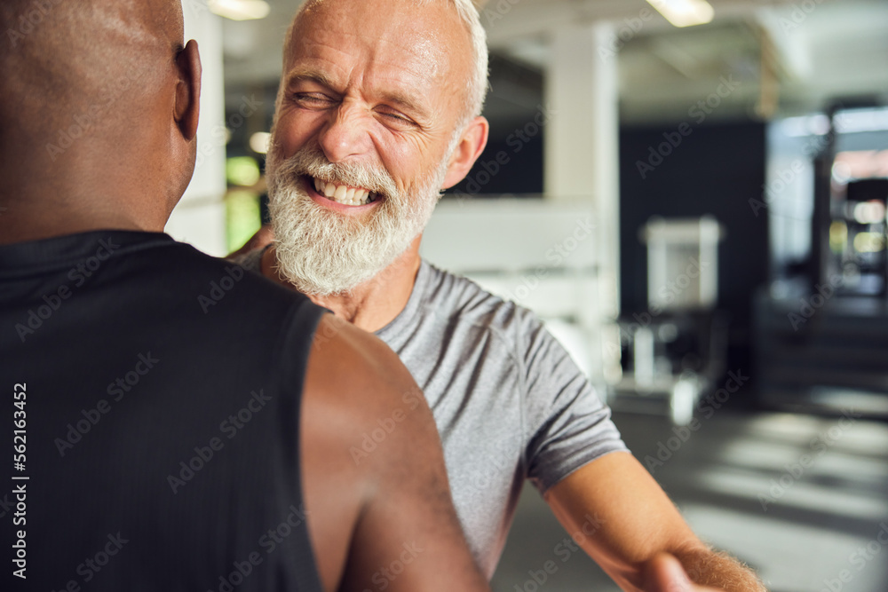 Mature man laughing with a friend in a gym Mature man laughing with a friend in a gym