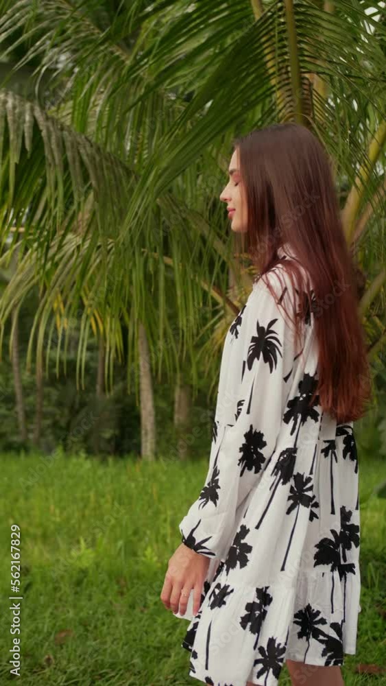 vertical video a girl walks along the road next to palm trees vertical video a girl walks along the road next to palm trees