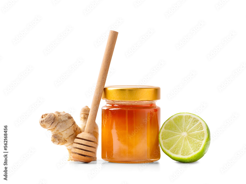 Honey in a jar with dipper , lime and ginger on a white background Honey in a jar with dipper , lime and ginger on a white background