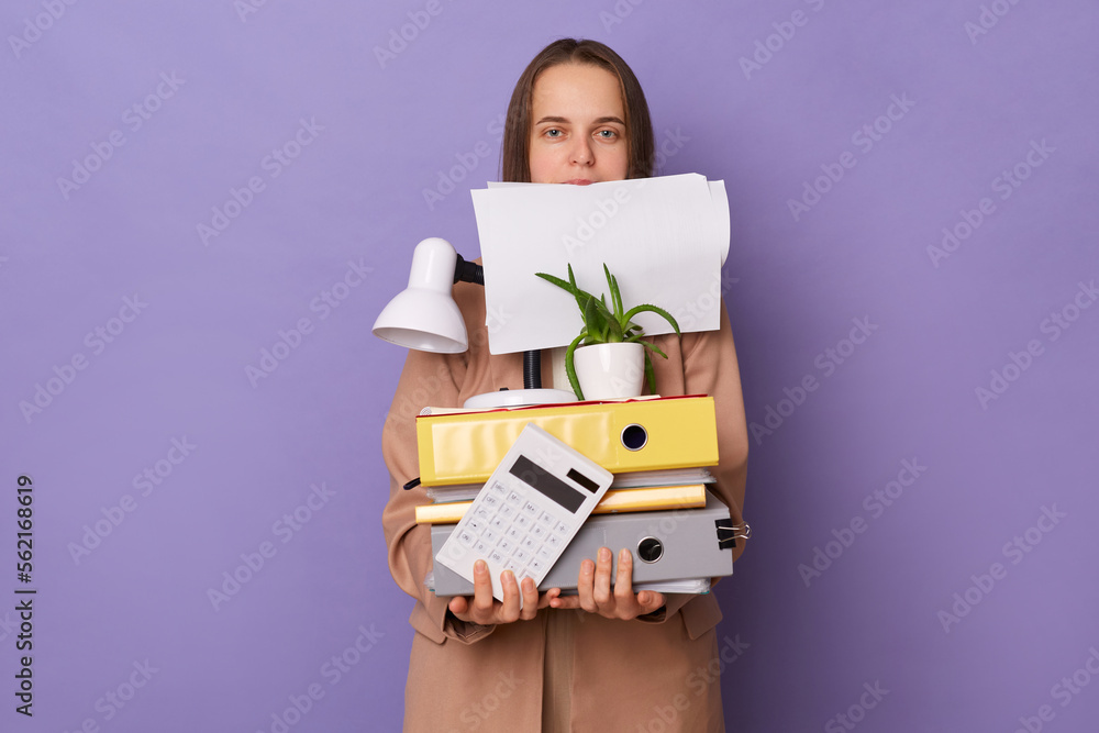 Portrait of busy funny Caucasian woman wearing official style jacket holding folders isolated over purple background, holds empty papers with her teeth, looking at camera. Portrait of busy funny Caucasian woman wearing official style jacket holding folders isolated over purple background, holds empty papers with her teeth, looking at camera.