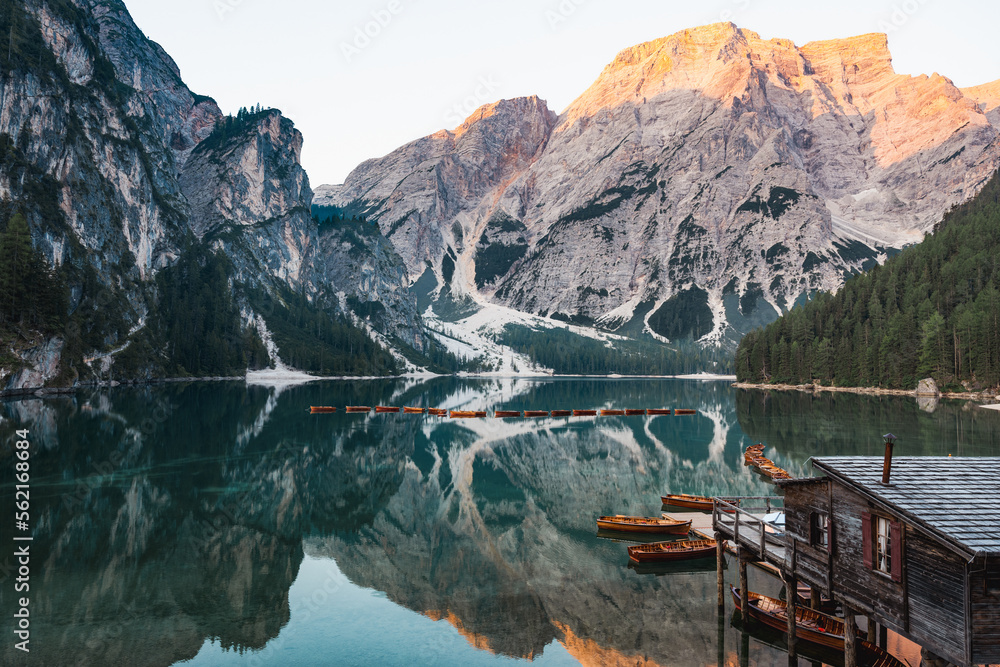 Stunning view of the Lake Braies (Lago di Braies) with some wooden boats and beautiful mountains reflected in the water. Lago di Braies is an alpine lake in the Dolomites, Italy.