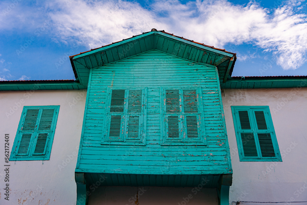 Facade of a vintage house with a veranda and shutters against the sky.