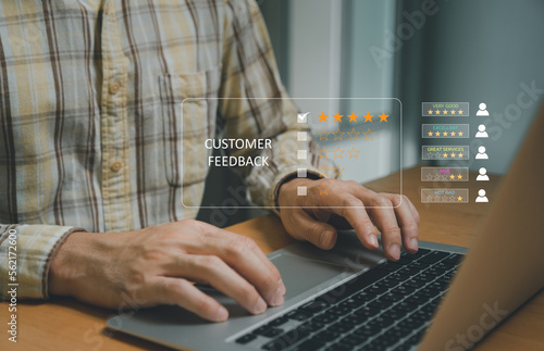 Selective focus at finger of business man while point finger to choose feedback on excellent customer service with five star score with smile. Service evaluation concept with futuristic icon.