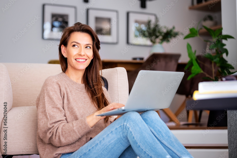 Attractive woman sitting at home and using laptop Attractive woman sitting at home and using laptop