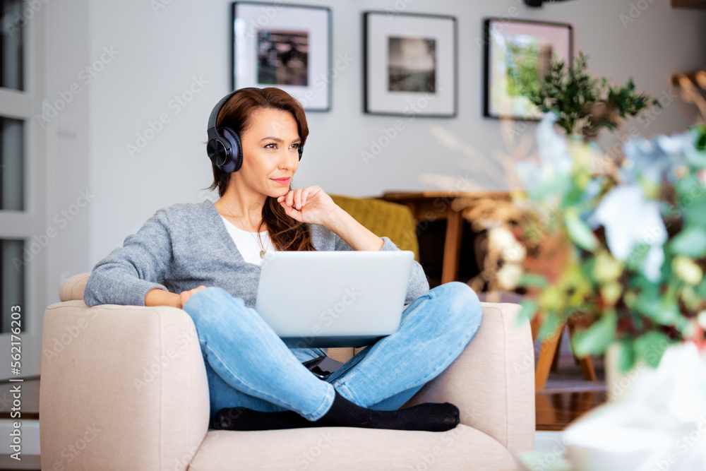 Attractive woman relaxing at home and using earphone and laptops Attractive woman relaxing at home and using earphone and laptops