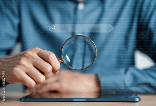 Businessman use magnifying glass Search On Virtual Screen Data Search Technology Search Engine Optimization. Man use tablet to Searching for information. Using Search Console for data.