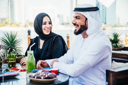 Happy couple spending time in Dubai. man and woman wearing traditional clothes having a conversation in a cafe