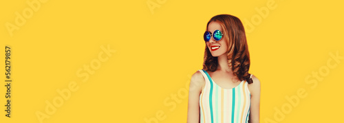 Summer portrait of happy smiling woman looking away wearing sunglasses posing on yellow background © rohappy