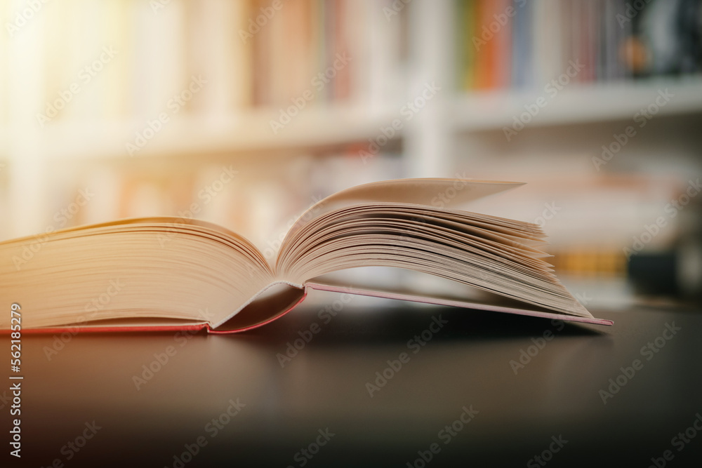 Open book on a black table. Library in the background. Book on table close up. Open book on a black table. Library in the background. Book on table close up.