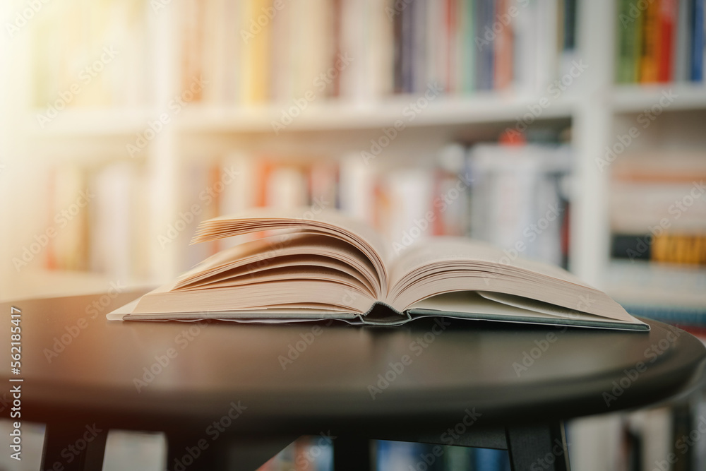 Open book on a black table. Library in the background. Book on table close up. Open book on a black table. Library in the background. Book on table close up.