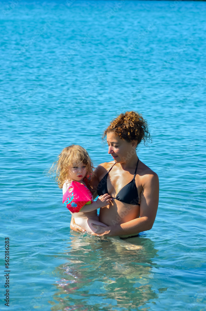Mom and her little daughter on vacation bathing at the edge of a lagoon Mom and her little daughter on vacation bathing at the edge of a lagoon