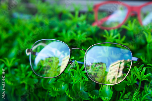 Glasses for vision, lie on artificial green grass, close-up.