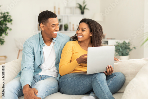 Smiling young african american lady show laptop to guy, recommend website and app for work and study
