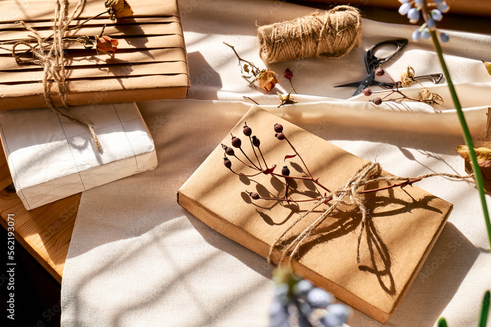 Gifts wrapped in recycled paper and decorated with dried flowers on linen  tablecloth. Natural aesthetic. Zero waste, plastic free, trendy, handmade  gift package. Photos