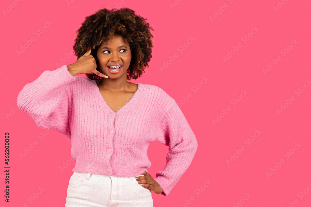 Happy pretty young african american curly woman with braces calling at imaginary phone, enjoy talk Happy pretty young african american curly woman with braces calling at imaginary phone, enjoy talk
