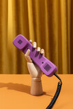 Wooden hand dials a number on a retro phone. Conceptual photo