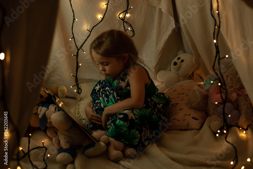 the girl is playing and reading a book in the hut