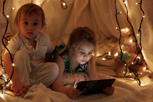 children sit in the hall and look at the tablet