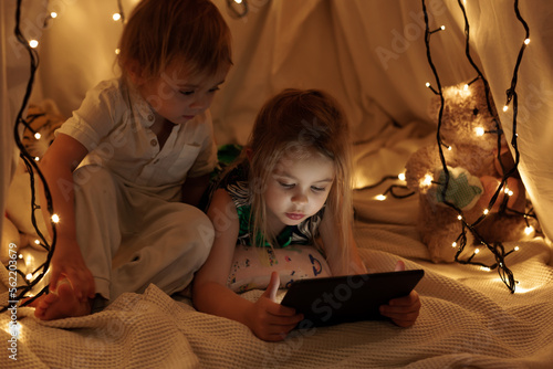 children sit in the hall and look at the tablet